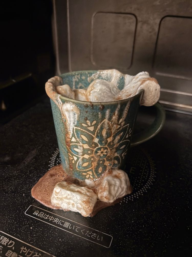 電子レンジの中でカップから溢れた溶けかけのマシュマロ