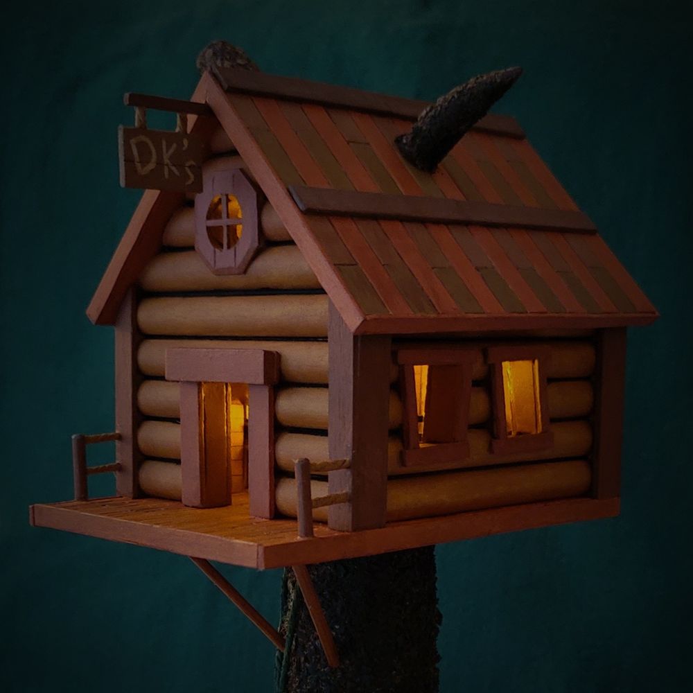 Dimly lit shot of DK's treehouse with a warm glow coming from a tea light inside. Hand-crafted model.
