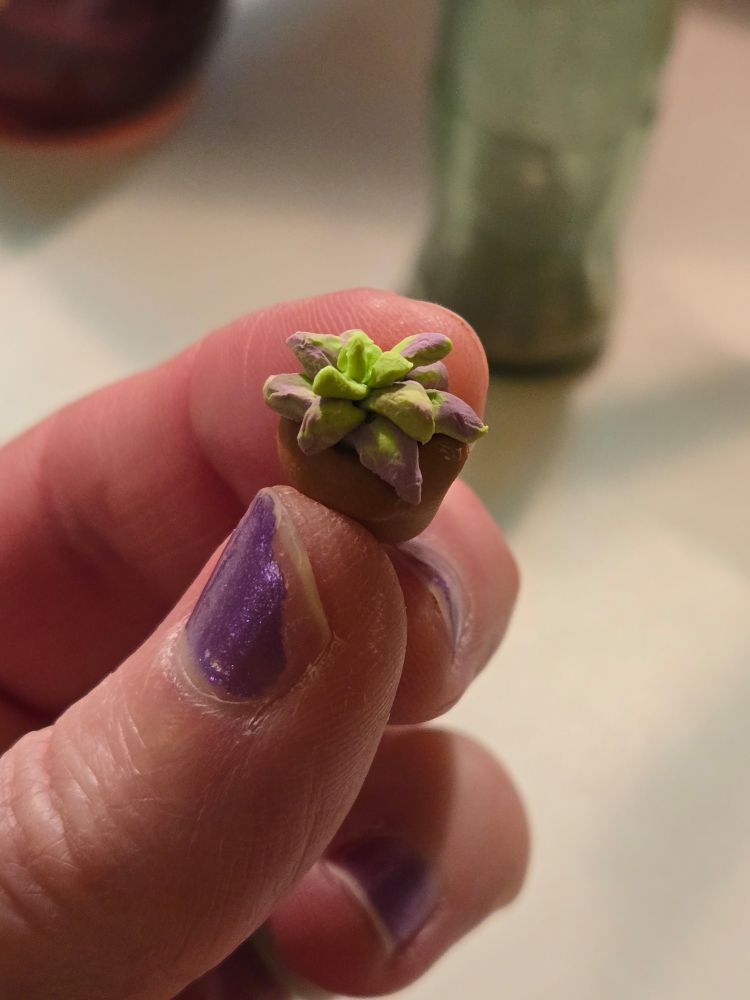 Fingers holding tiny clay plant