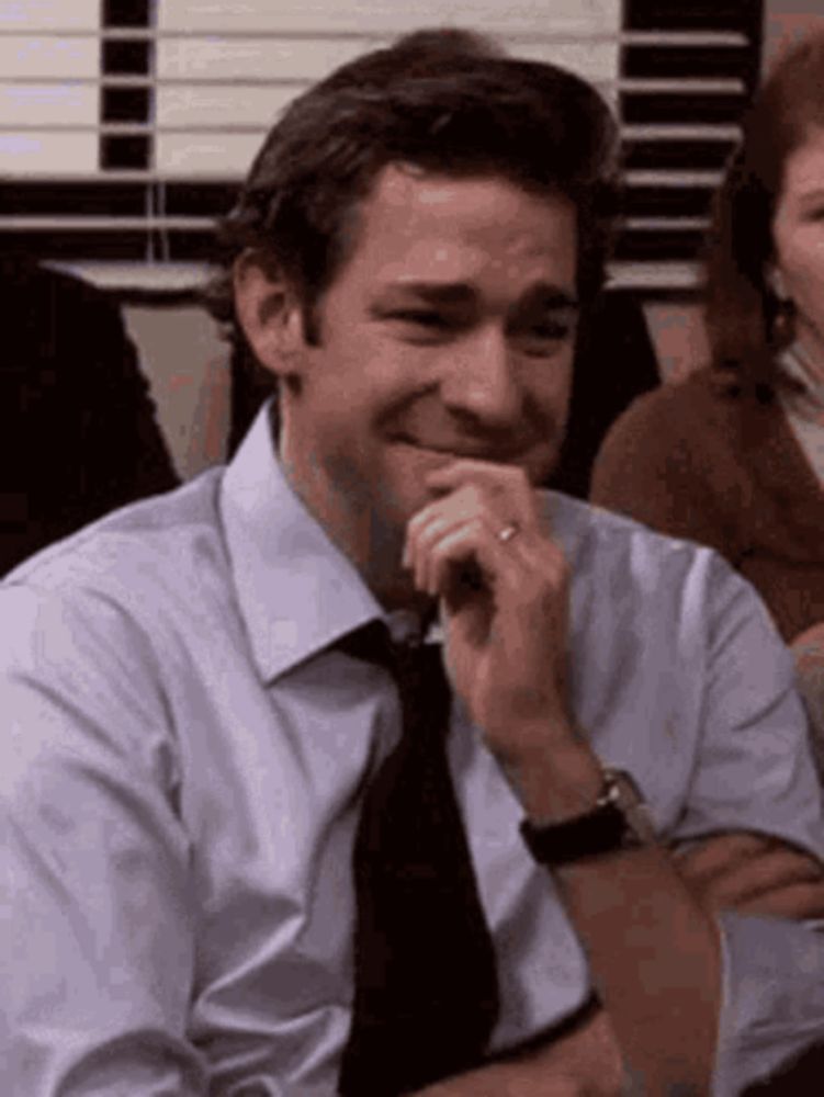 a man in a suit and tie is laughing while sitting at a table .