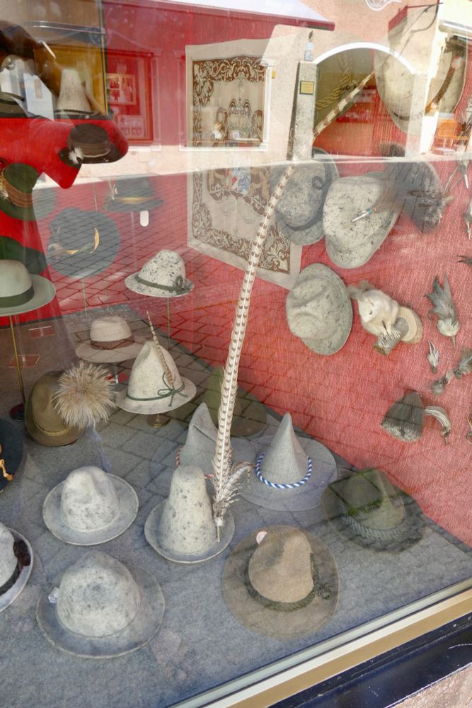 Window of a shop in Berchtesgaden, Bavaria selling traditional hats, one of which has a very large feather attached to it.