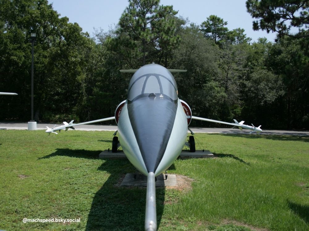 Nose-on view of F-104 Starfighter jet parked in front of trees at a museum. Shows how tiny the wings are and why it's sometimes referred to as a "missile with a man in it". They actually put people in this sci-fi lawn dart! Photo by @machspeed.bsky.social