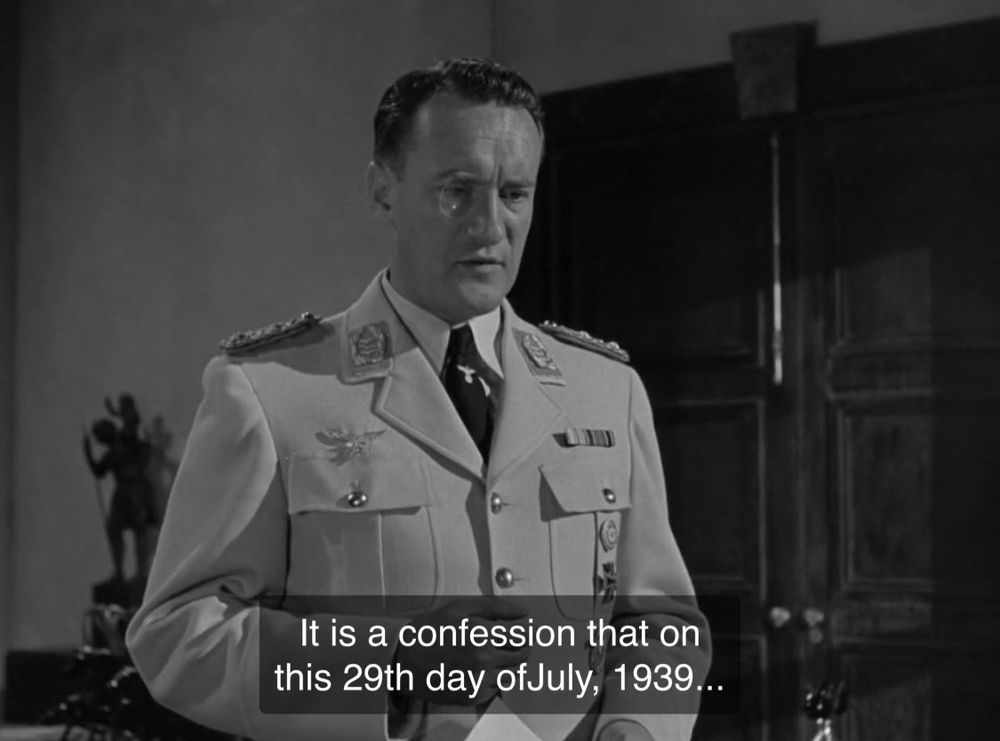 1 Screenshots from the movie "Man Hunt" (1941): First, a man in a decorated military uniform stands in a formal room with dark wooden doors and a statue in the background, holding a piece of paper, with the subtitle "It is a confession that on this 29th day of July, 1939..." The frame is in black and white, with sharp contrasts and a dramatic, suspenseful atmosphere typical of wartime thrillers.