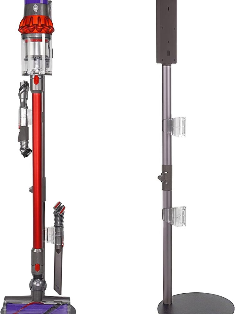 Rot-lila-grauer Dyson Staubsauger aufrecht in Ständer stehend. Rechts im Bild der graue Ständer, mit runder Metallbodenplatte, ca. 30 cm Durchmesser, nochmal ohne Sauger.