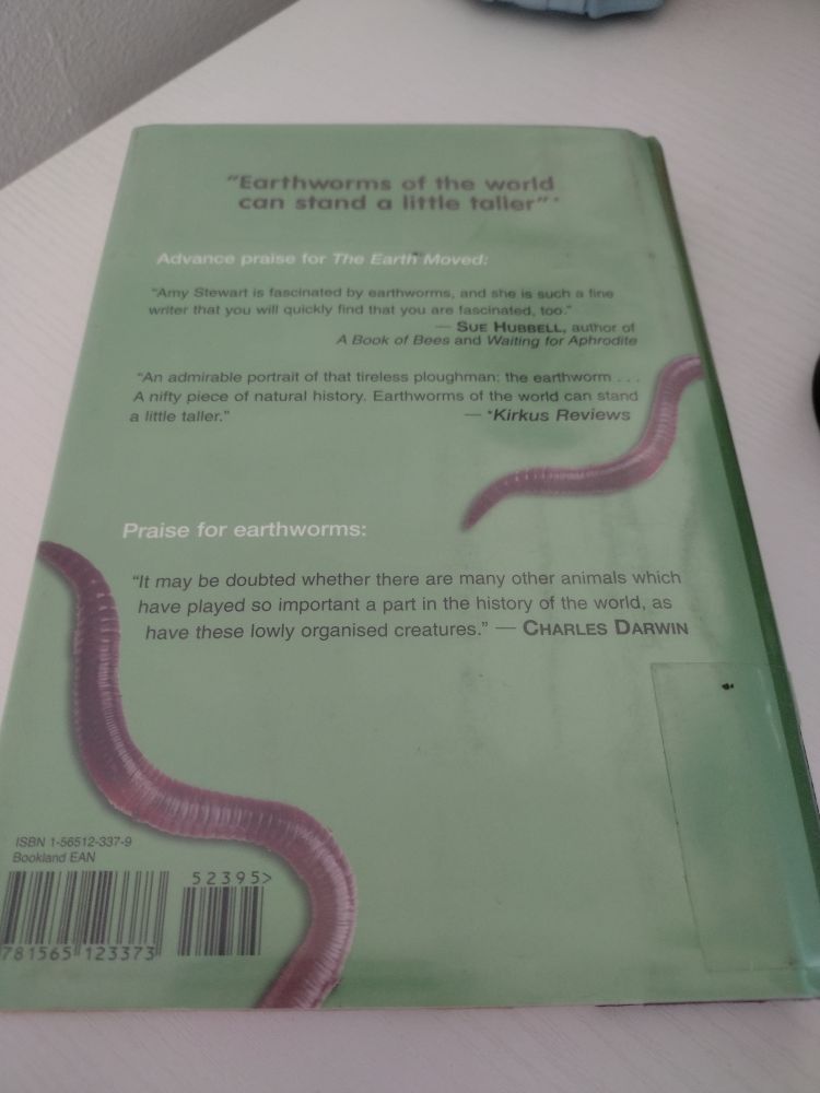 Back cover for the book The Earth Moved by Amy Stewart. Green color with review text with two pinkish earthworms wriggling to each side of the book cover.