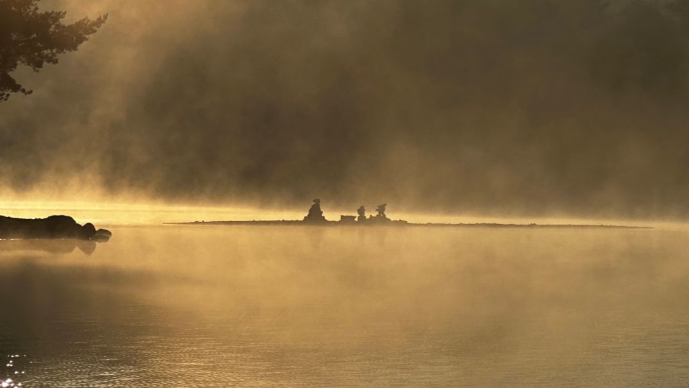 Eine see mit Dunst und aufeinander gestapelte steinen.