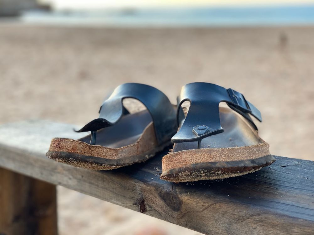 Meine urlaubsschuhe, birkenstock zehendrenner, auf dem handlauf stehend, an einem Strand....