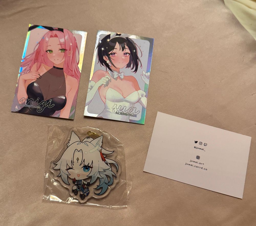 two mizi and sua photocards and a feixiao keychain