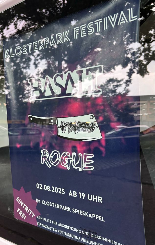 dunkelblaues Plakat hinter Autoscheibe: KLOSTERPARK FESTIVAL.
BASALT
TRISTESSE (Das Logo ist Fleischerbeil)
ROGUE
02.08.2025 AB 19 UHR
IM KLOSTERPARK SPIESKAPPEL
EINTRITT FREI
KEIN PLATZ FÜR AUSGRENZUNG UND DISKRIMINIERUNG
VERANSTALTER- KULTURBÜHNE FRIELENORF