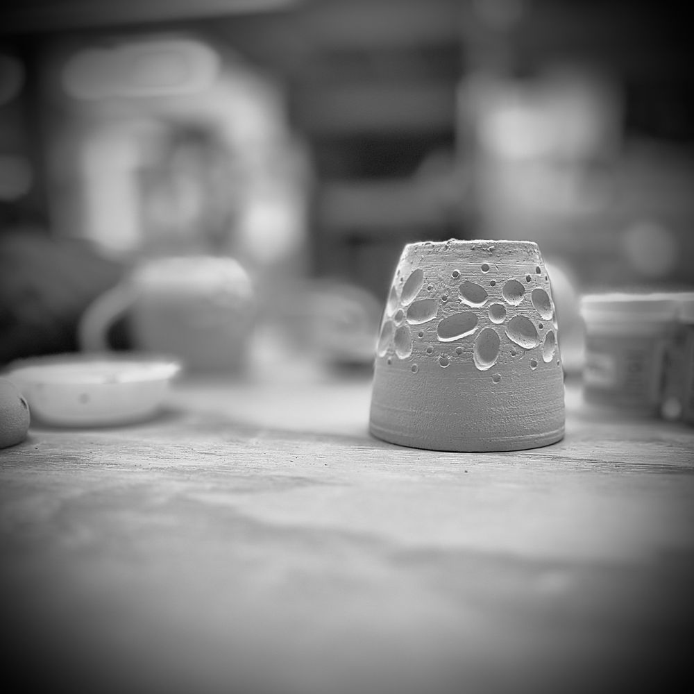 A small, carved tumbler waits on glaze.