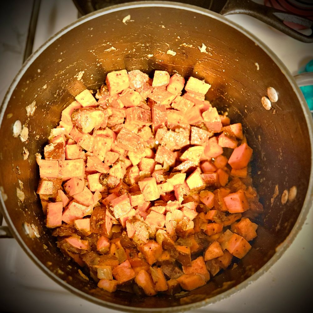 A bag of cubed sweet potatoes cooking in a curry with sautéed onion.  