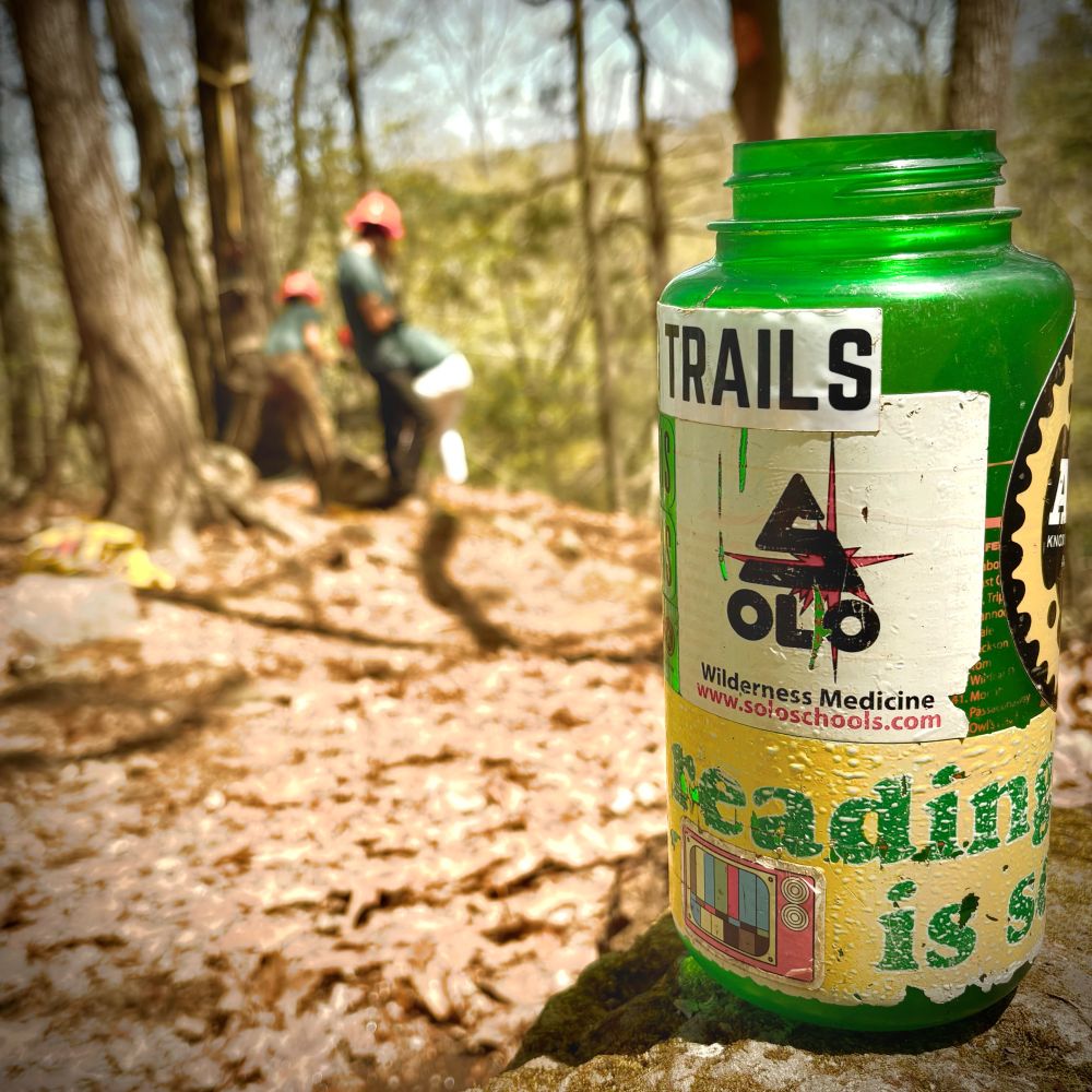 Picture of a super cool Nalgene covered in stickers raising the overall value to about $60.00.  A trail crew is in the background doing amazing things.