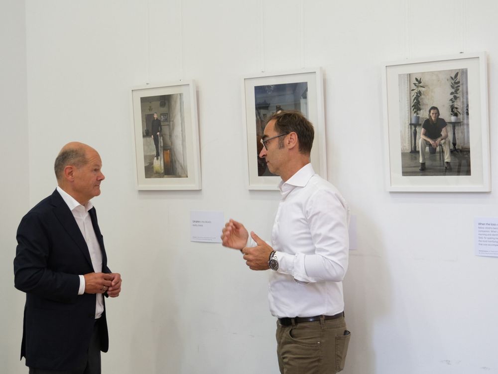 Olaf Scholz bei der Besichtigung der Foto-Ausstellung "Bizarre Normalität" des Fotografen Hans-Hugo Hoffmann (rechts).