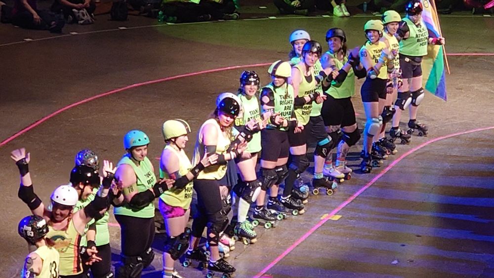 Minnesota Roller Derby skaters wearing new shirts with Trans Athletes Belong Here written on them