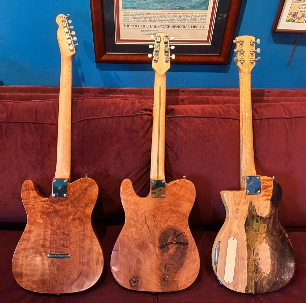 The same three guitars, but showing their backs. The M2C's back has a large area of epoxy resin inlay covering pest-eaten parts of the redwood body.