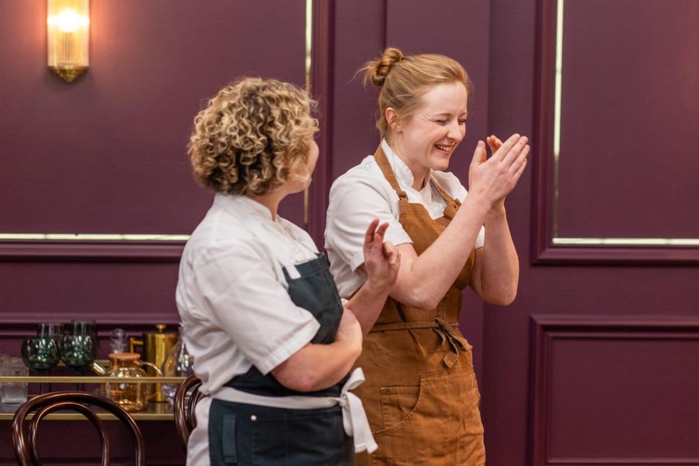 Two female chefs, one clapping and overcome with emotion