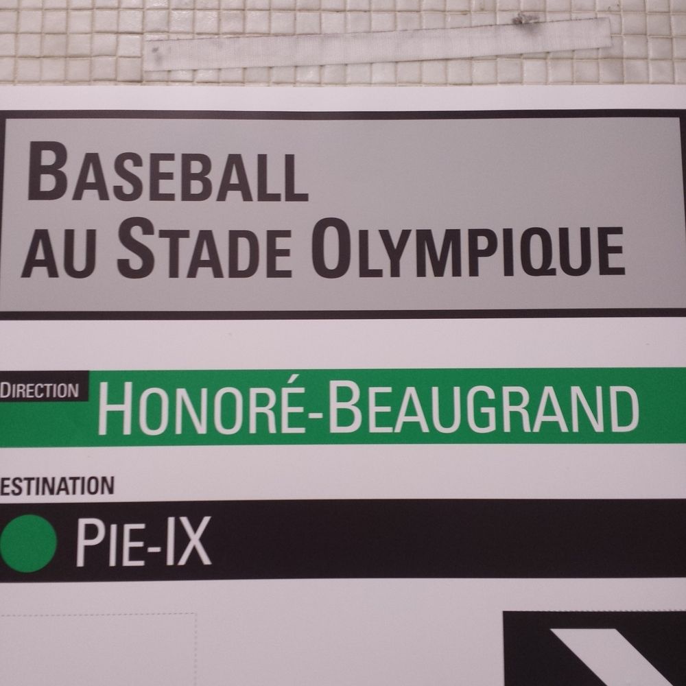 Sign that says "Baseball au Stade Olympique" (Baseball at Olympic Stadium) above the name of the Metro station and travel direction.