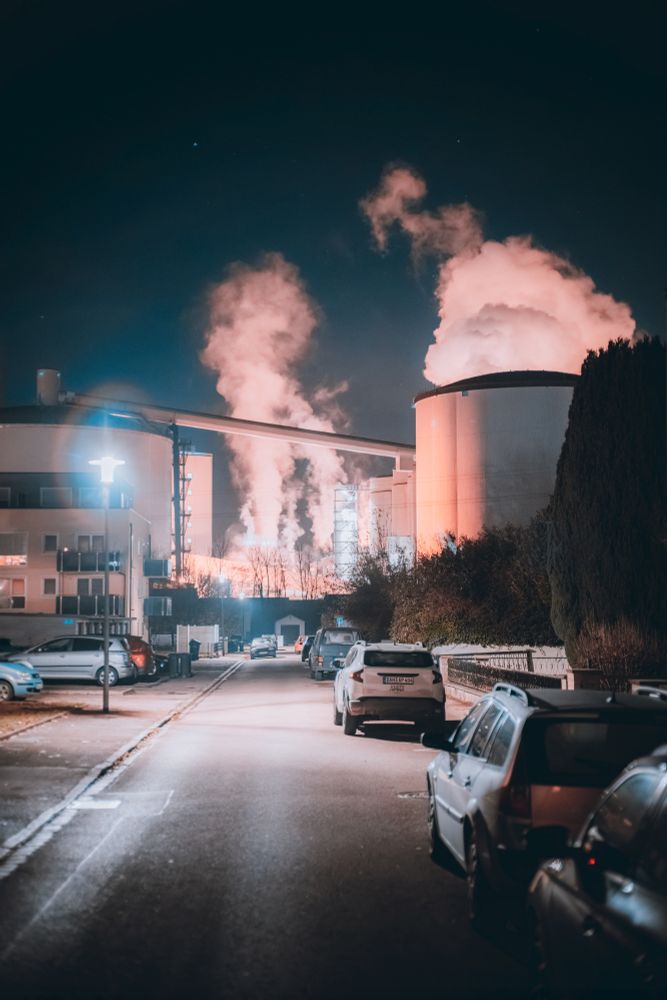Nachtaufnahme einer Strasse an deren Ende sich Industrie befindet.