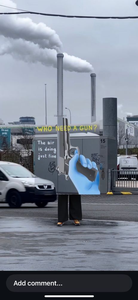 AI painting by @iam_zlu of gun that matches backdrop of factory smokestacks and passing white car. Sign says, “who needs a gun? The air is doing just fine.”

Source: https://www.instagram.com/reel/DHIsslzikvx/?igsh=Mm84amZvaGY0cGht