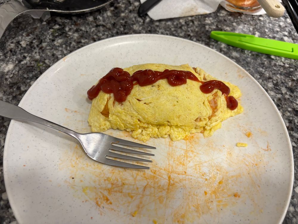 Another picture of an omurice that is more tightly packed and less messy, with ketchup covering it lengthwise.