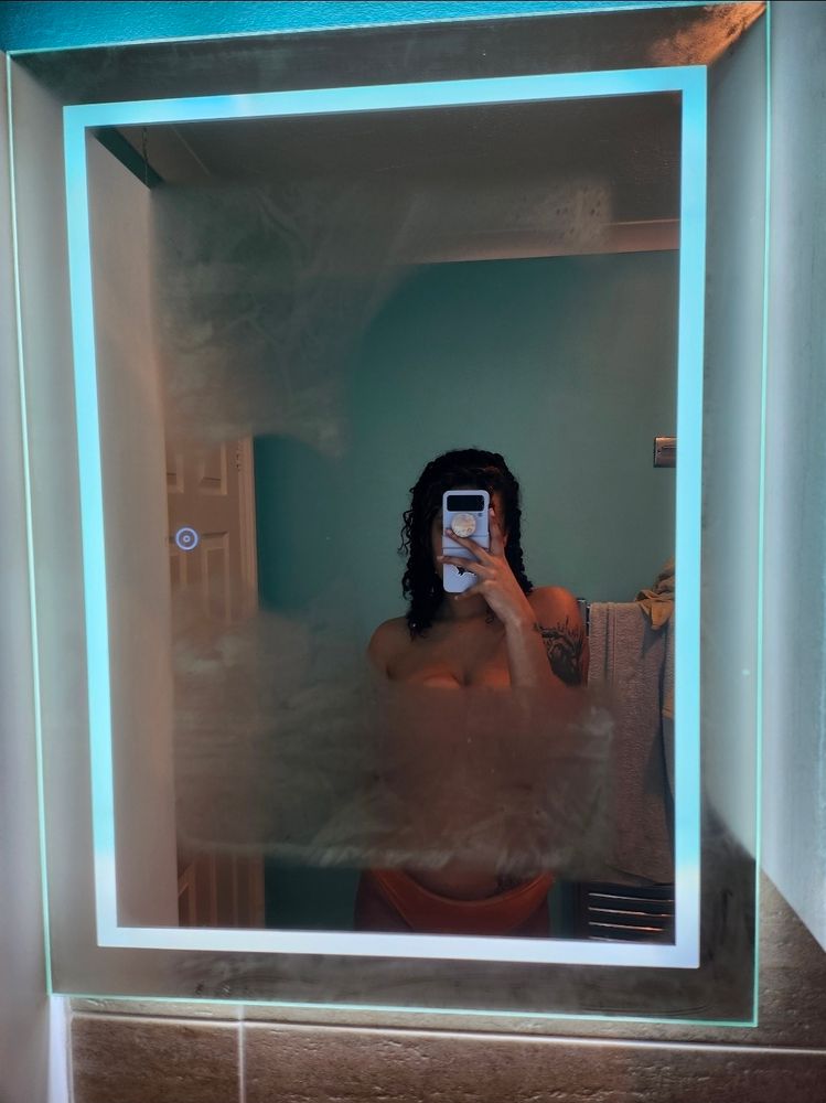 Bathroom mirror selfie of Rain, the phone covering her face. The condensation on the mirror covers up the breasticles.