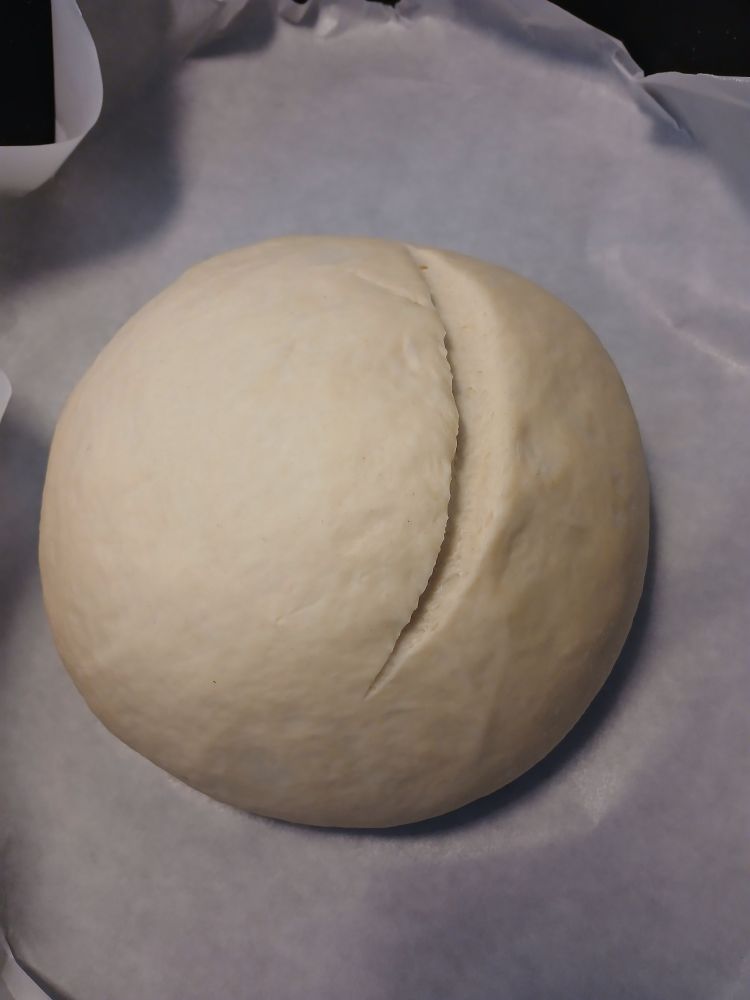 A round of sourdough with a crescent shaped cut along the top.