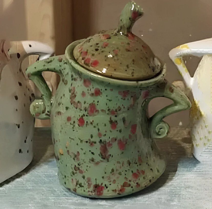 Um pote, talvez um acúcareiro, feito de louça, que simula o movimento que o ser humano faz com as mãos na cintura, quando esta indignado. O potinho é tortinho pra um lado, com as 'asinhas' assim, na cintura, como quem pergunta ou comenta: audacia!