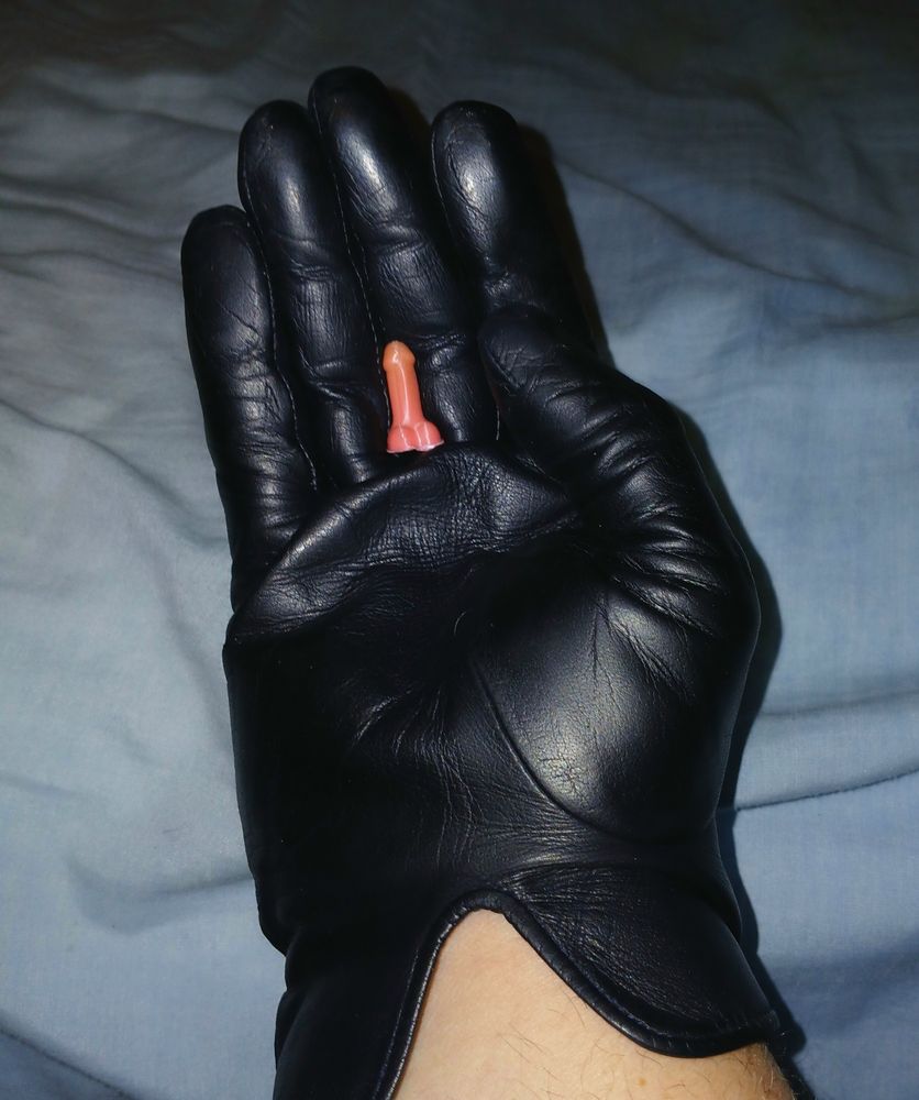 A tiny 3d printed cock and balls held by a leather gloved hand 