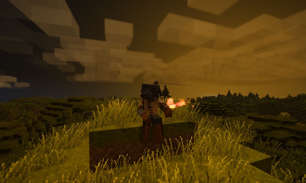 Blue man sitting on top of a hill holding a torch. Behind him the sun is setting creating a cozy ochre to navy gradient across the sky.