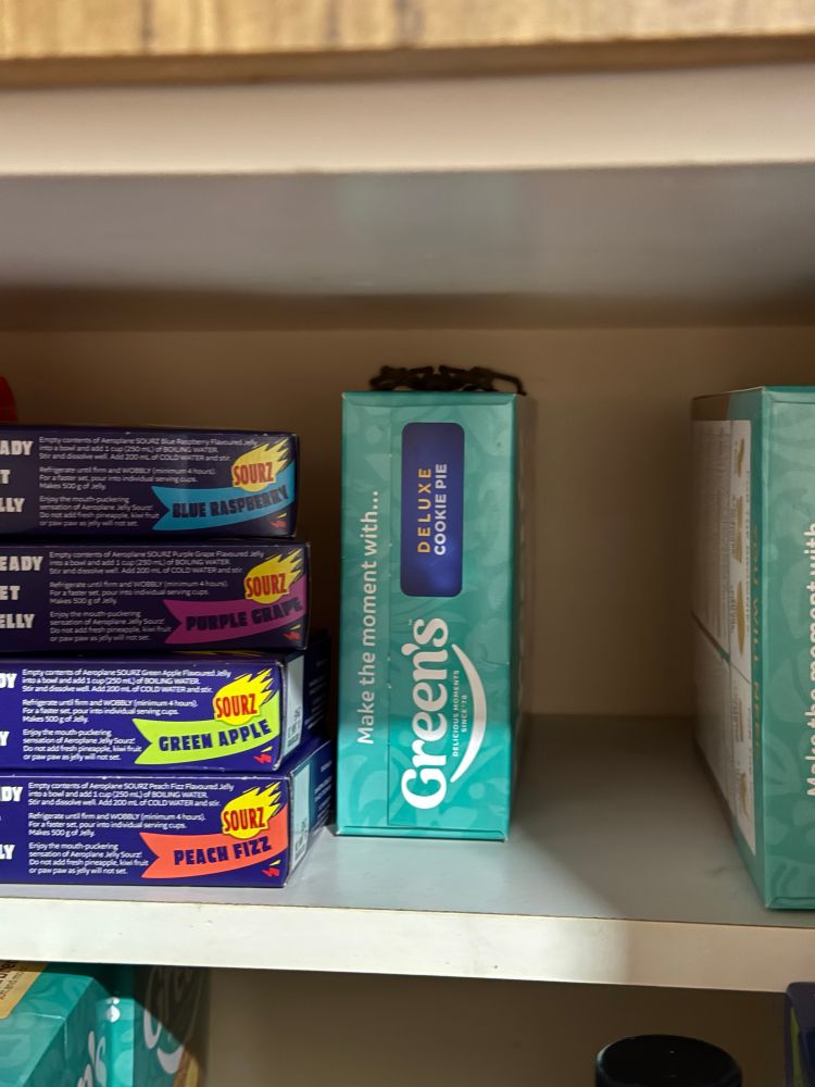 A large black spider sitting on top of a Green box of a cookie pie baking mix