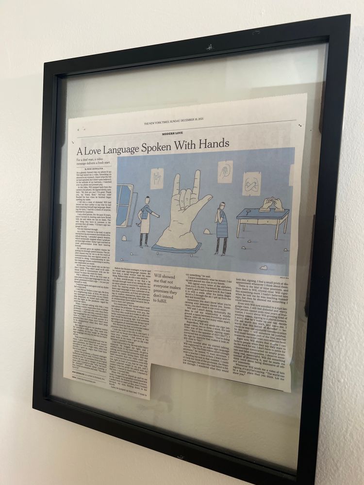 A cut-out printed version of Ross Showalter’s 2021 Modern Love essay “A Love Language Spoken with Hands” is framed and mounted on the wall.
