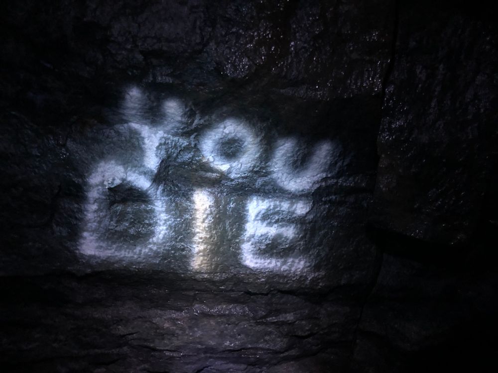 Graffiti on the wall of a mine reads, “YOU DIE”