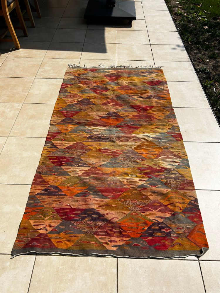 scruffy old moroccan rug airing on a sunny terrace 
