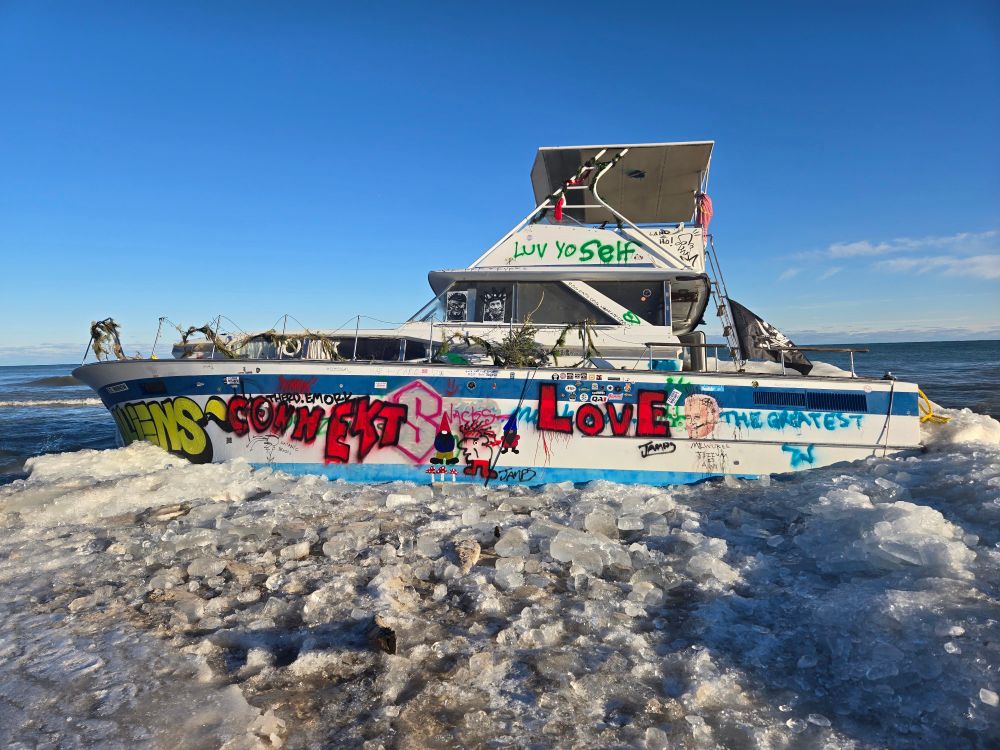 The mystery boat that froze to the shoreline in Milwaukee, tagged with various graffiti and stickers