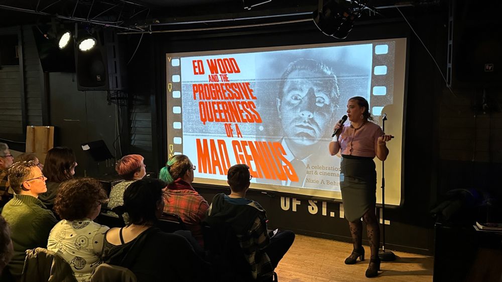 Photo of a presentation at a bar with the title “Ed Wood and the Progressive Queerness of a Mad Genius”