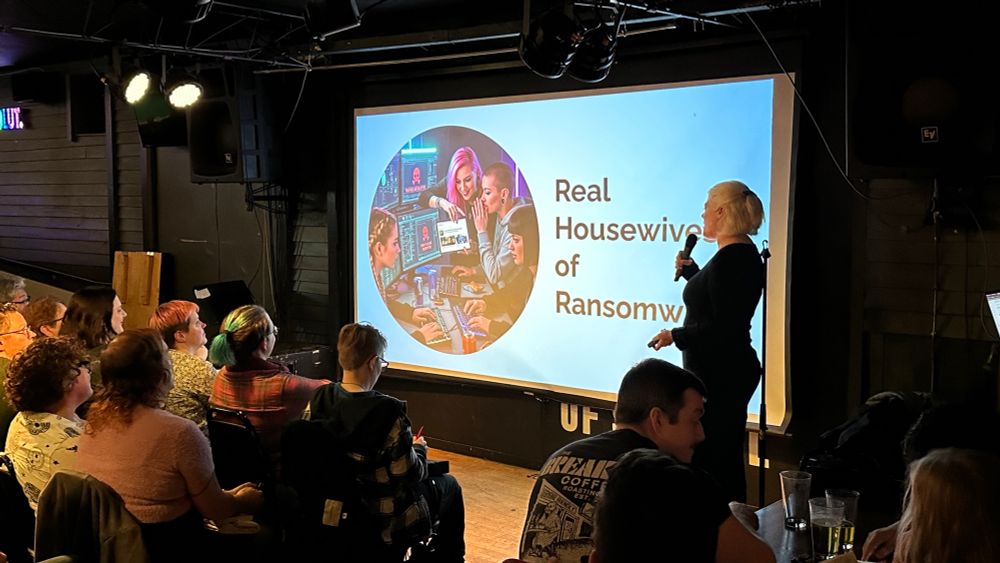 A woman giving a presentation with the title on screen, “Real Housewives of Randomware”