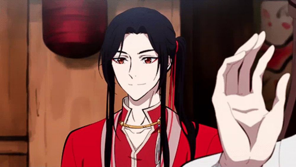 a man with long black hair and red eyes is giving a high five