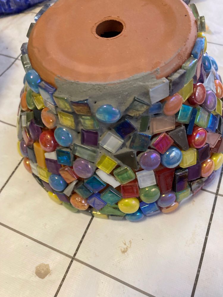 Terracotta pot number 2 partly covered with mosaic tile some are round and some are fragments.