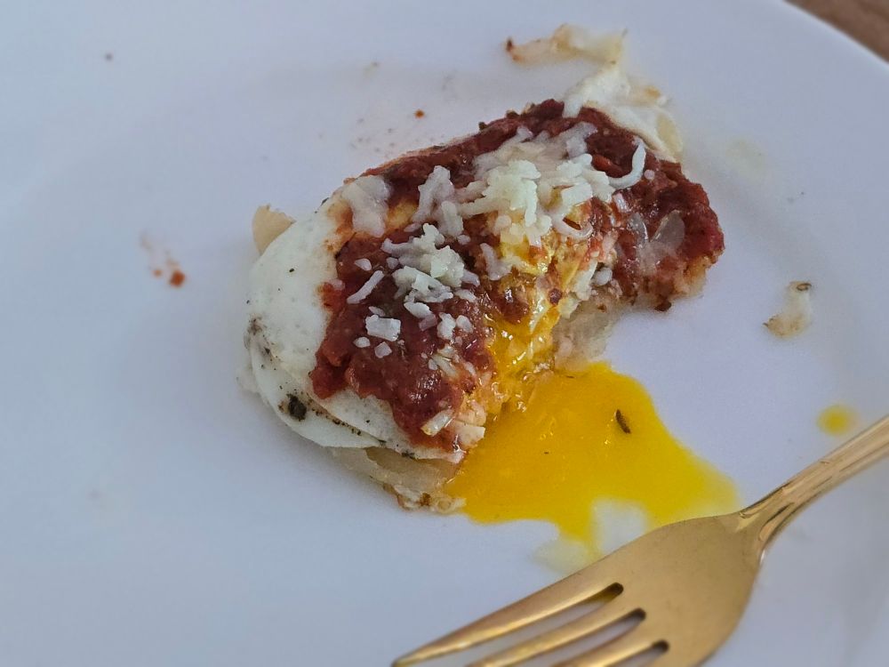 A little mini pancake made of fried sourdough starter, topped with a fried egg, pizza sauce, and mozzarella cheese.