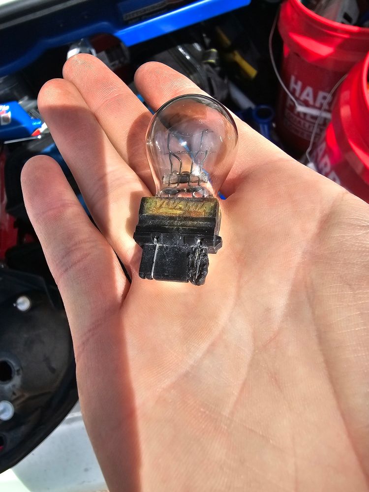A brake light bulb suffering from heat damage on the right lead due to a high resistance connection caused by corrosion in the socket.