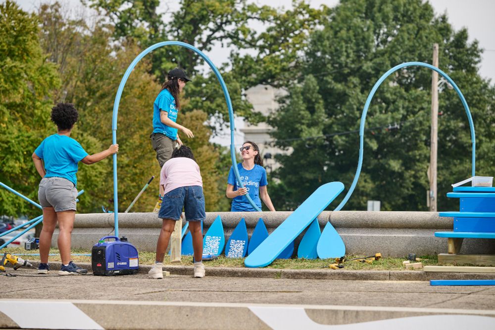 Four young people install blue decorative elements in Fairmount Park in Philadelphia.
