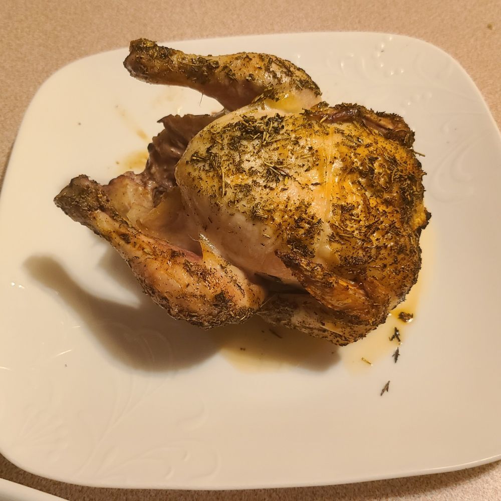 Cornish game hen fresh from the oven. It's covered in rosemary, thyme, sage, garlic and salt. 