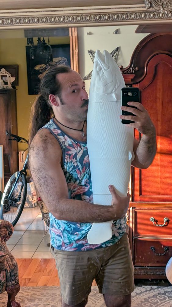 A hairy artist holding a 3 foot 3D printed Atlantic Salmon. 