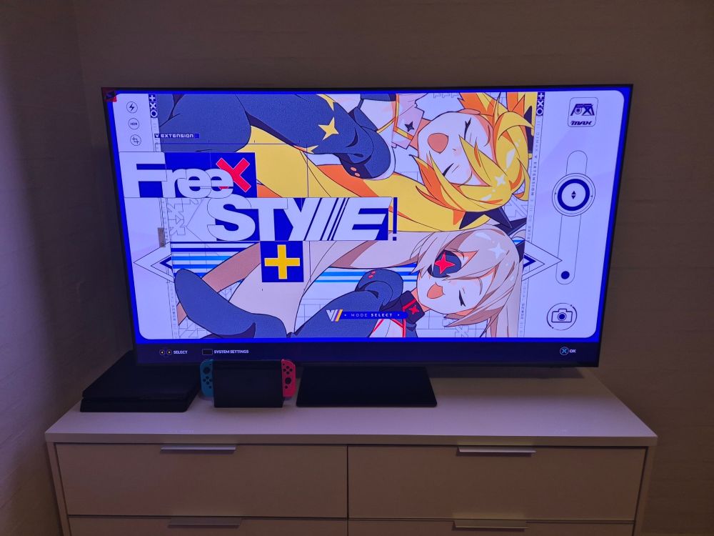 A photo of a new 55" 2025 model OLED TV connected to a PS4 Slim and Nintendo Switch, while showing the menu of Djmax Respect with the V Extension 3 menu theme.