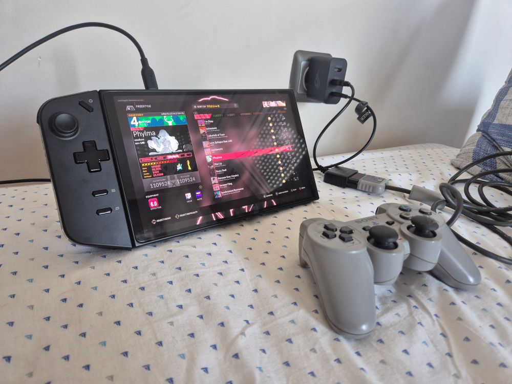 A photo of a Lenovo Legion Go running Djmax Respect V connected to a Rog 65w charger that is also connected to a DualShock 1 via a cheap PS to USB adapter