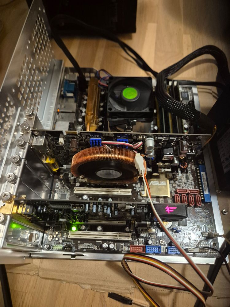 A photo of an ASUS M2N-SLI DELUXE motherboard on a motherboard tray with a GeForce 7600GT GPU and Sound Blaster X-Fi installed