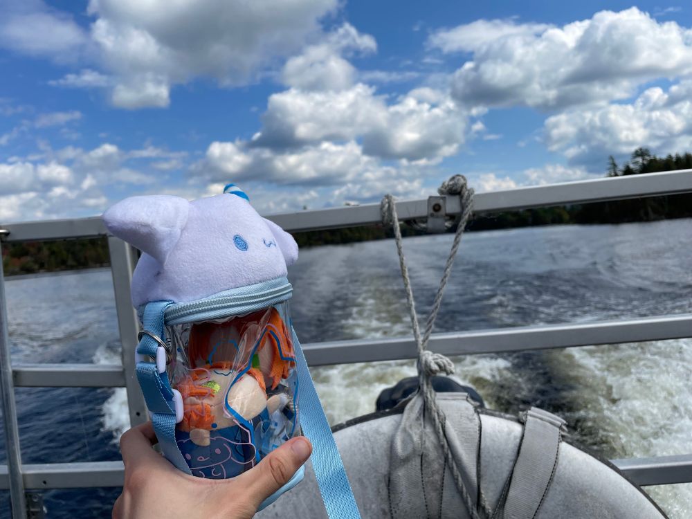 The Cinnaroll pouch with the Leos is on a boat in front of rippling water.