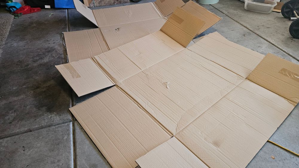 Two large unfolded cardboard boxes on a cement floor.