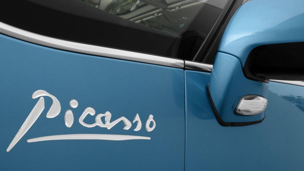 closeup of a blue Citroen car wing mirror showing the ‘Picasso’ signature branding.