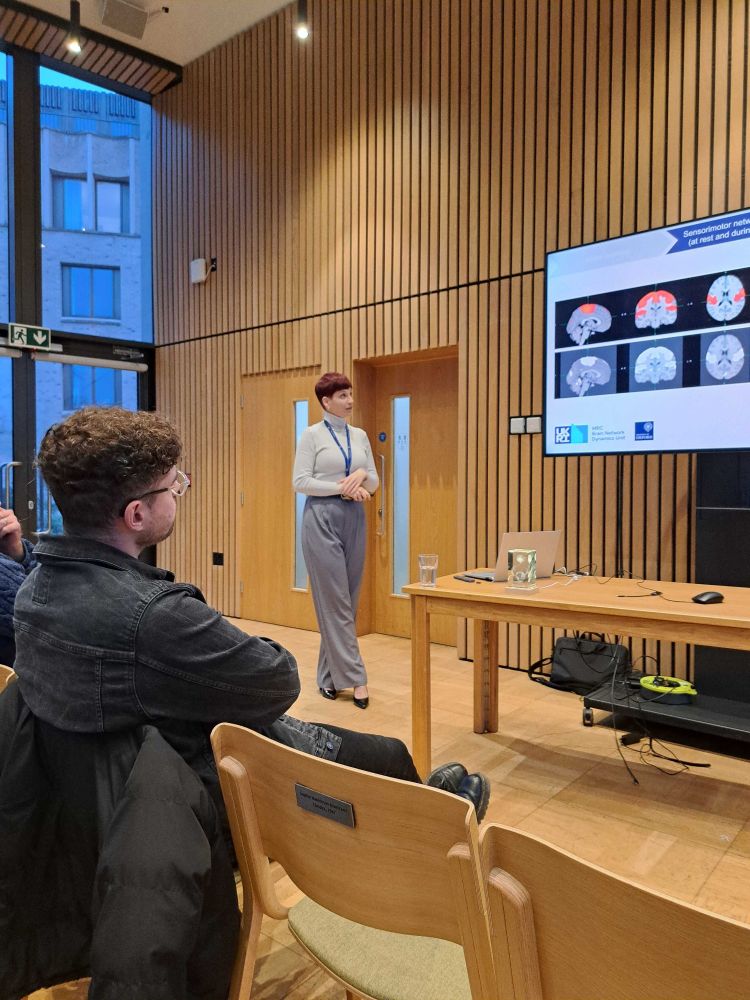 A woman presenting a PowerPoint slide with MRI brain images